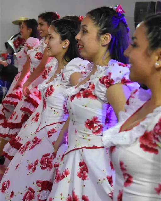 Bailarinas de Kahuira con vestidos blancos y rojos en fila durante Fiestas Patrias